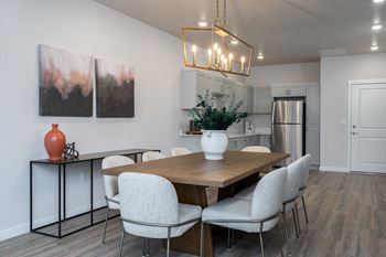a dining room with a table and chairs and a kitchen in the background